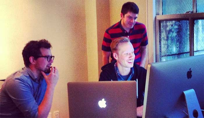 Three guys looking excitedly at a computer